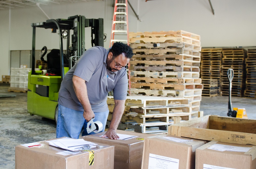 Man Taping Boxes in Warehouse